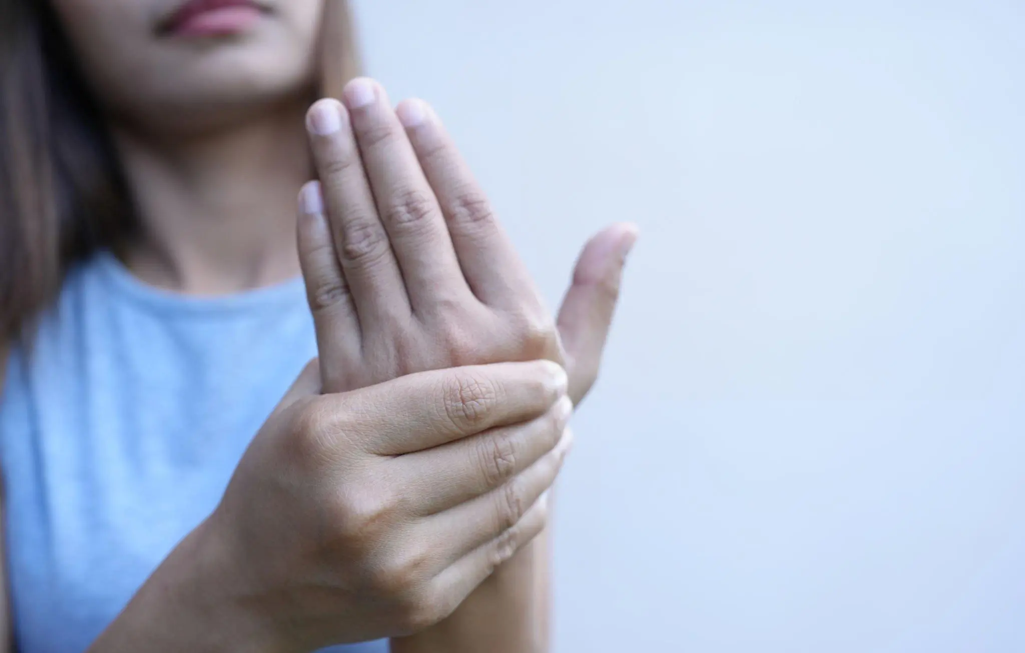 Close-up of a person seated with their hands clasped over one foot, highlighting discomfort, pain, or tingling commonly associated with Peripheral Neuropathy and its various causes.