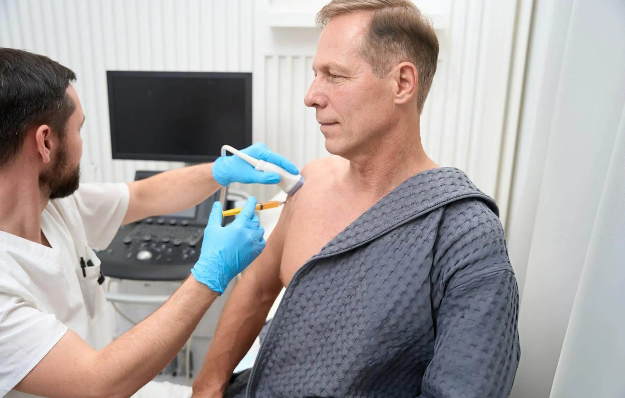 Medical professional using an ultrasound machine to guide a shoulder injection for stem cell therapy targeting rotator cuff disease.