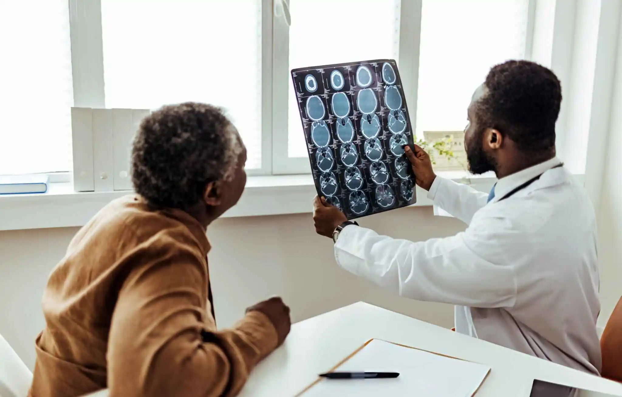 Medical professional presenting brain scans to a patient in a clinic setting, representing advancements in stem cell therapy for migraines and chronic headaches.