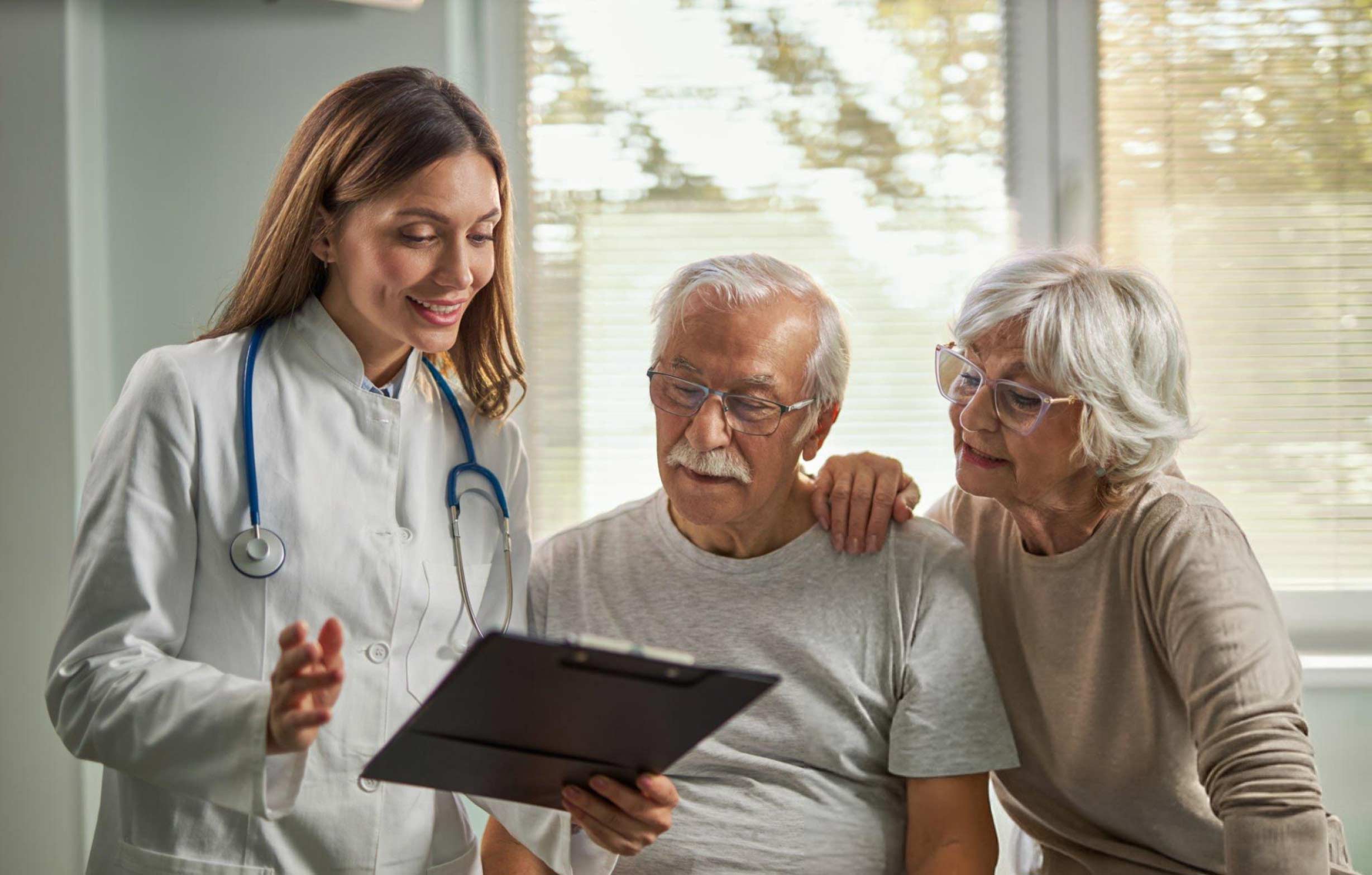 A doctor discusses a non-surgical stem cell treatment plan with a senior couple at our clinic in Westwood, MA.