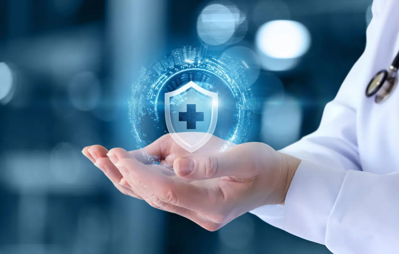 Hands of a doctor holding a glowing medical shield, representing health protection.