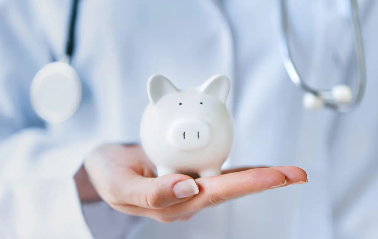 Piggy bank and a stethoscope on a blue background, representing healthcare costs.