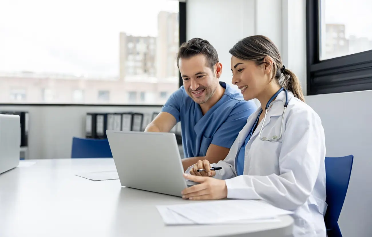 Two healthcare professionals collaborating and reviewing patient information on a laptop.