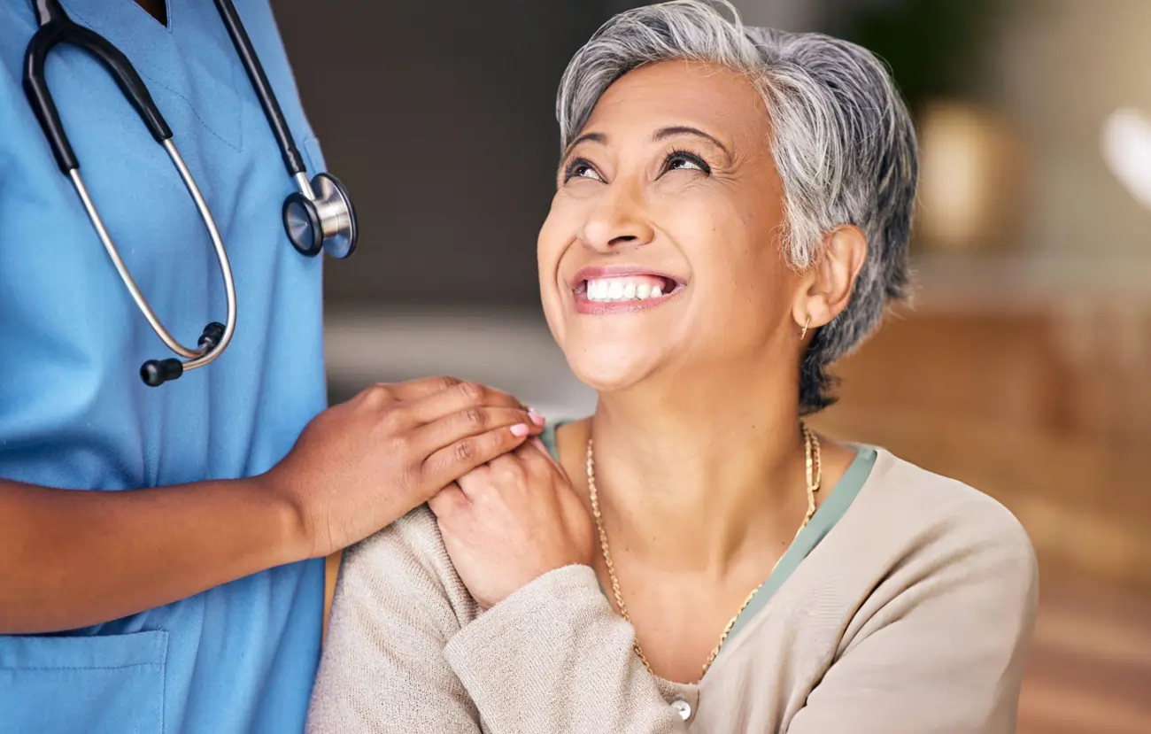 Nurse reassuring an elderly patient with a kind smile.