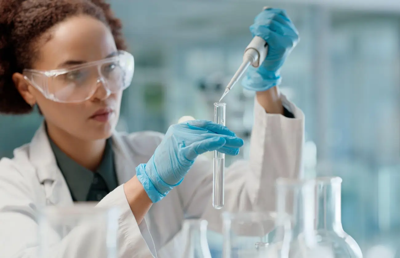 A dedicated female scientist works with a pipette and test tube in a sterile laboratory setting.