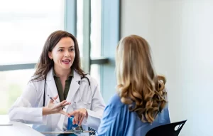 Female doctor in a white coat consulting with a patient in a bright medical office.