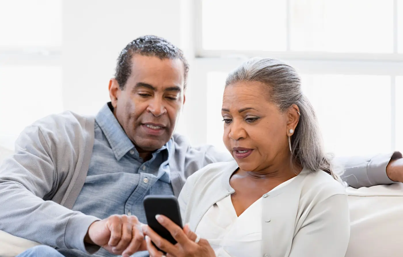 Senior couple researching stem cell therapy options on a smartphone for joint pain relief.