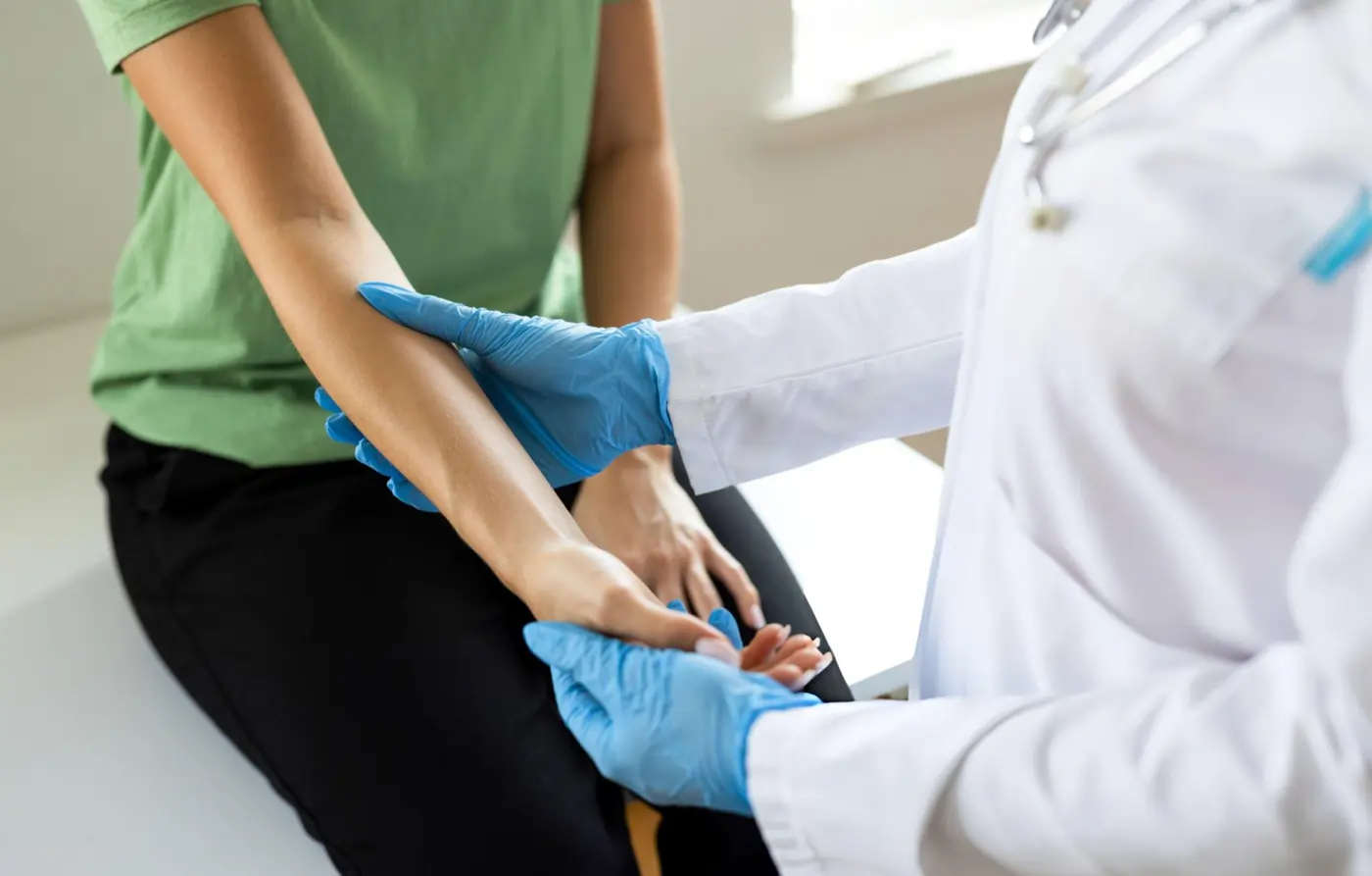 Smiling male doctor in white coat and stethoscope standing in a hospital hallway.