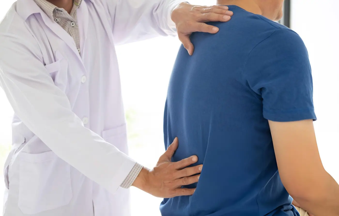 Doctor examining patient's back for spine health and lower back pain relief.