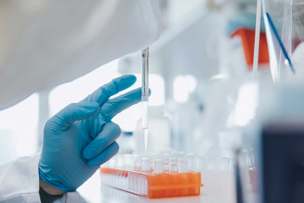 A medical professional in blue gloves using a pipette to process amniotic stem cell tissue in a sterile laboratory environment for Elk Grove patients.