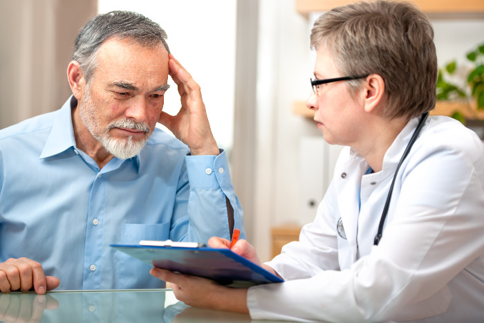 A doctor in a white coat explaining the benefits of exosome therapy and regenerative medicine to a patient during a consultation in Durham.