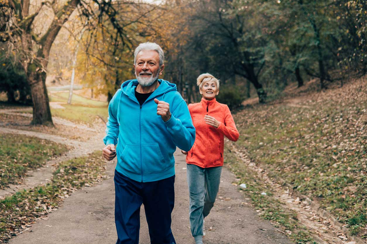 An active senior couple jogging in a Garland, TX neighborhood, maintaining bone density and muscle mass through regular exercise.