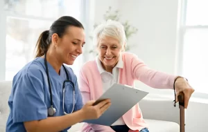Female healthcare professional reviewing medical documents with a smiling elderly woman using a cane during a clinic consultation.