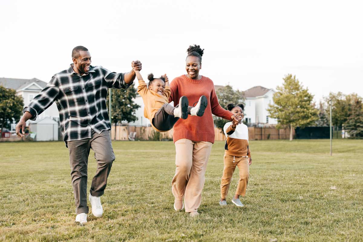 A happy, active family playing and running together on a green lawn, illustrating the quick recovery and return to normal daily life after regenerative therapy.