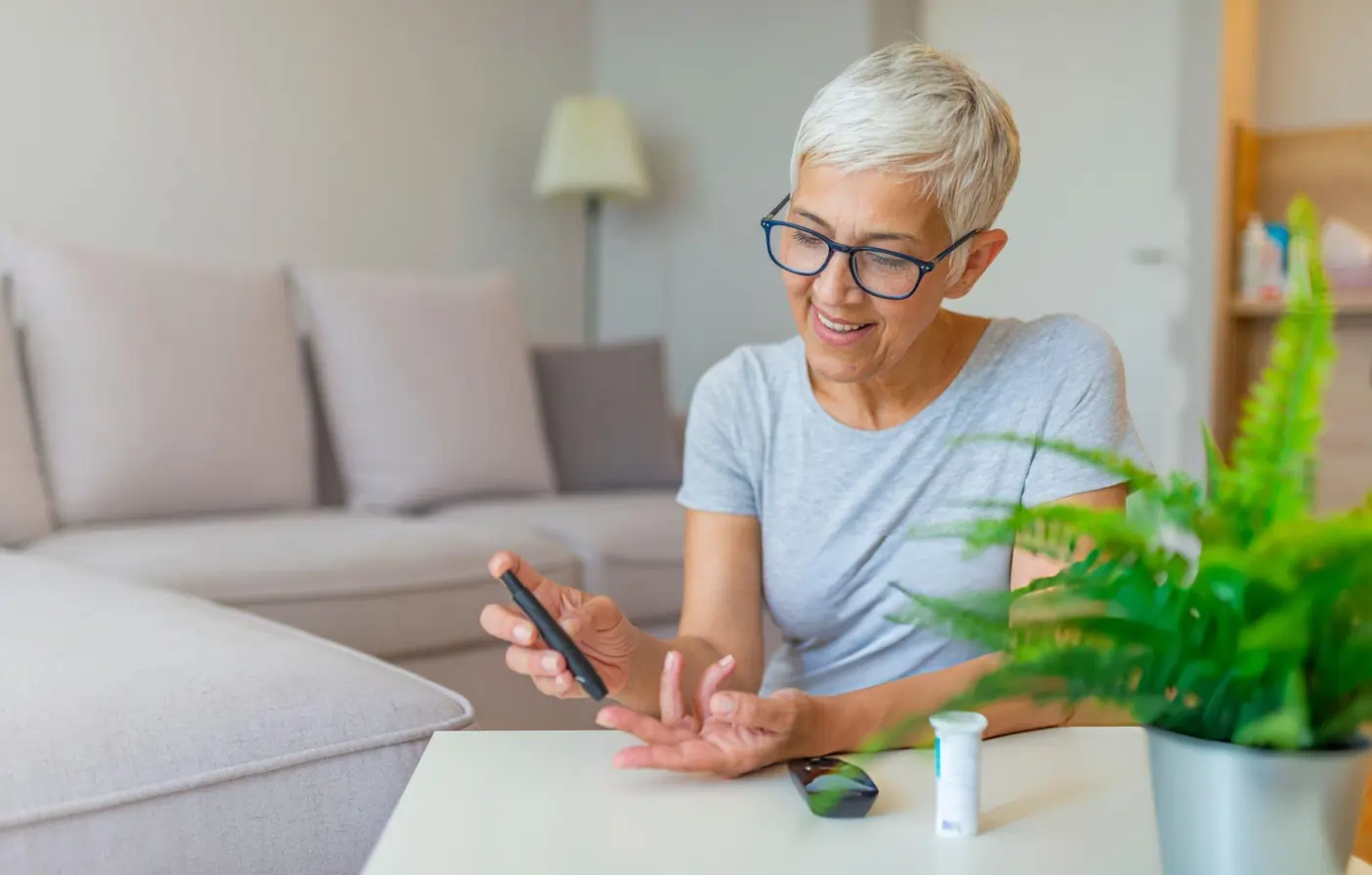 Senior woman using a glucose meter to check blood sugar levels at home.