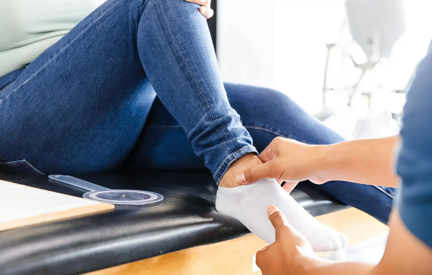 Clinician examining a patient's ankle during a stem cell therapy consultation at a regenerative medicine clinic