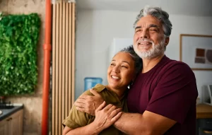 Smiling senior couple embracing each other at home, expressing love, happiness, and a healthy lifestyle.