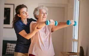 Older woman doing physical rehabilitation exercises with a therapist after stroke recovery treatment.