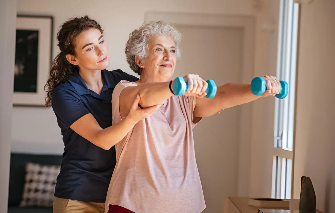 Older woman doing physical rehabilitation exercises with a therapist after stroke recovery treatment.