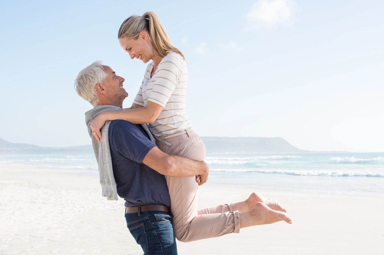 Happy couple embracing on a sunny beach after stem cell treatment