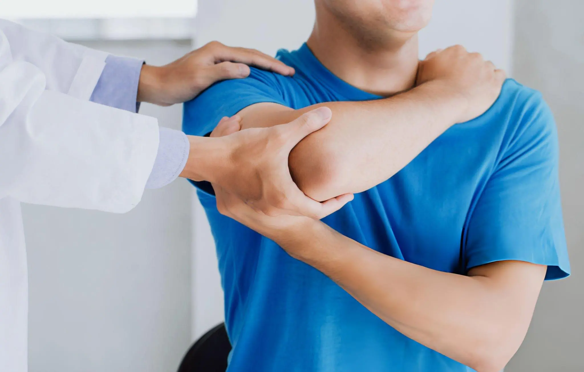 Doctor examining a patient's shoulder and elbow pain, a common concern among Olathe patients