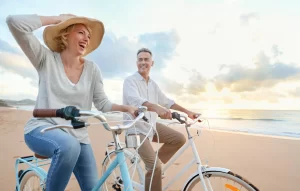 Happy mature couple riding bicycles on the beach
