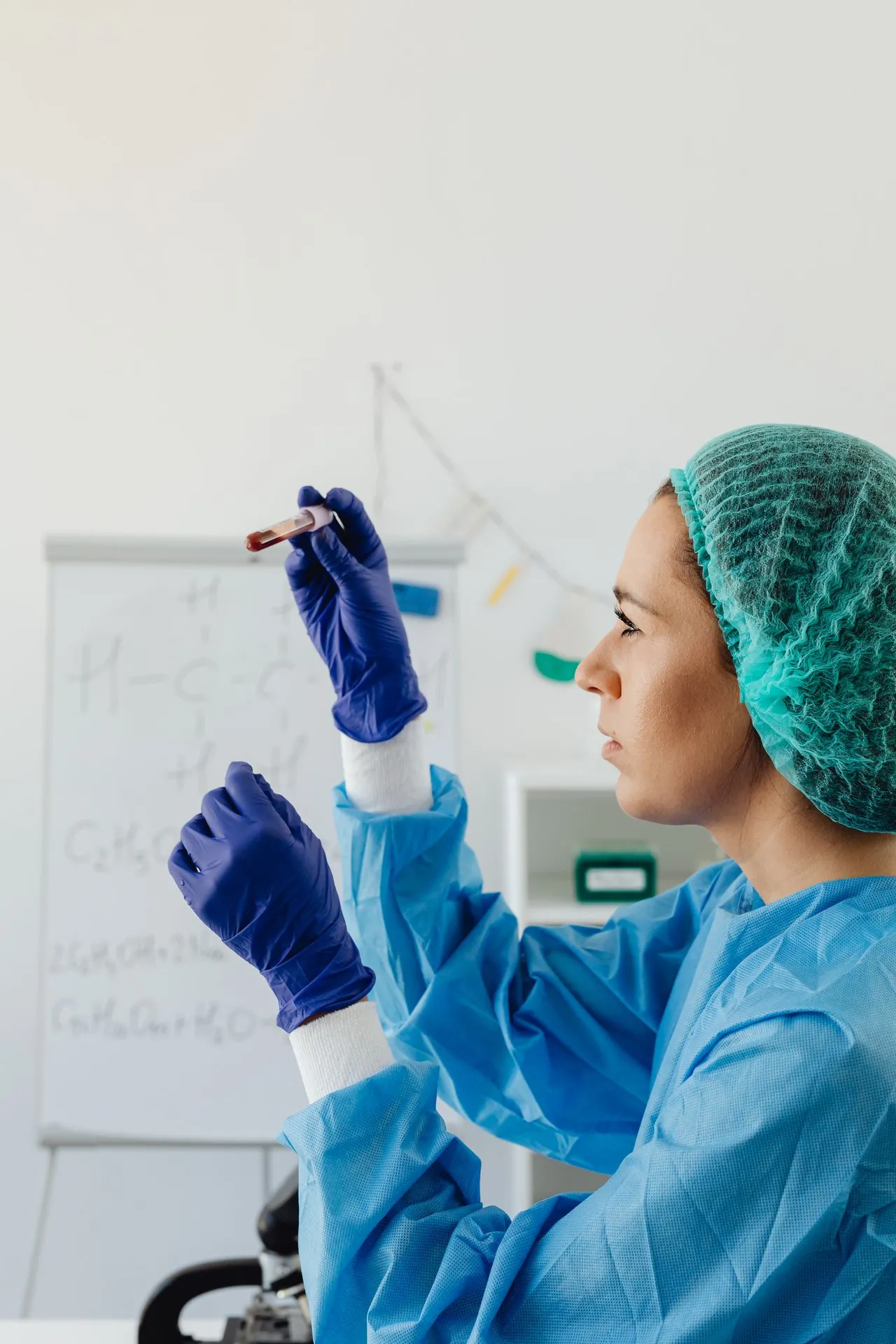 A lab technician in protective gear inspecting a blood sample vial in a certified laboratory setting.
