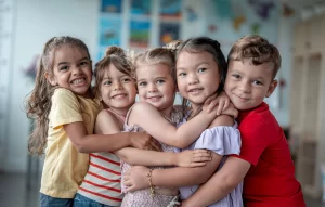Group of smiling children hugging during early autism intervention