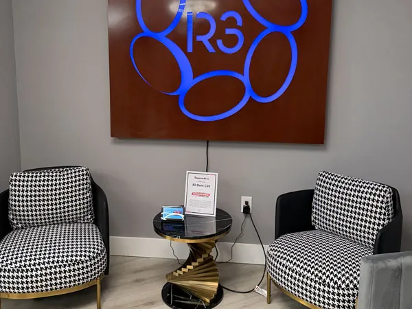 Illuminated blue R3 logo on a wood accent wall at R3 Stem Cell Orlando