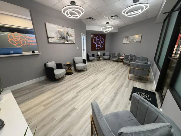 Spacious waiting room at R3 Stem Cell Orlando with modern gray seating and ring light fixtures